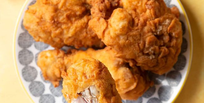 Close-up of a freshly fried chicken buttermilk batch in a cast iron skillet, emphasizing the crunchy texture and golden hue achieved through perfect frying, inviting anticipation for the first bite.