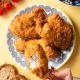 Close-up of a freshly fried chicken buttermilk batch in a cast iron skillet, emphasizing the crunchy texture and golden hue achieved through perfect frying, inviting anticipation for the first bite.