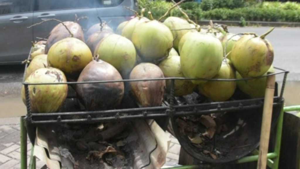 Suasana memanggang kelapa bakar di pantai,