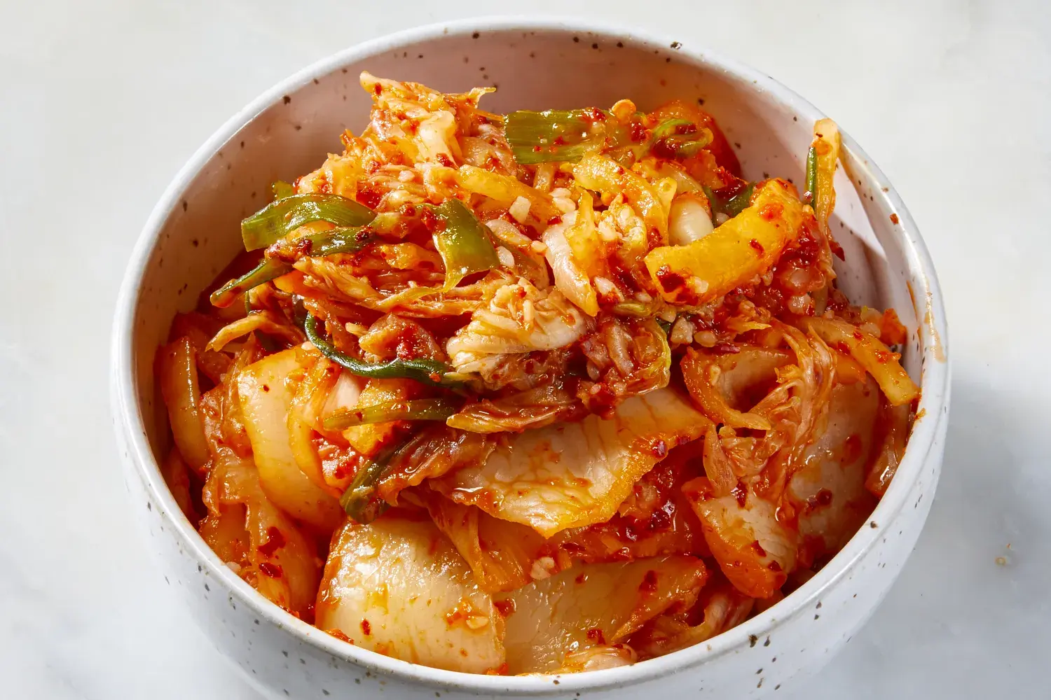 A group of people gathered in a kitchen, chopping vegetables and preparing kimchi together during Kimjang, highlighting the communal aspect and social importance of the tradition.
