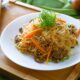 Sepiring bihun goreng klasik dengan tambahan sayuran segar dan potongan ayam, disajikan dengan taburan bawang goreng