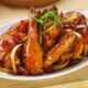 Ayam kecap manis dengan warna cokelat mengilap dan potongan daun bawang, tampak lezat dan menggugah selera