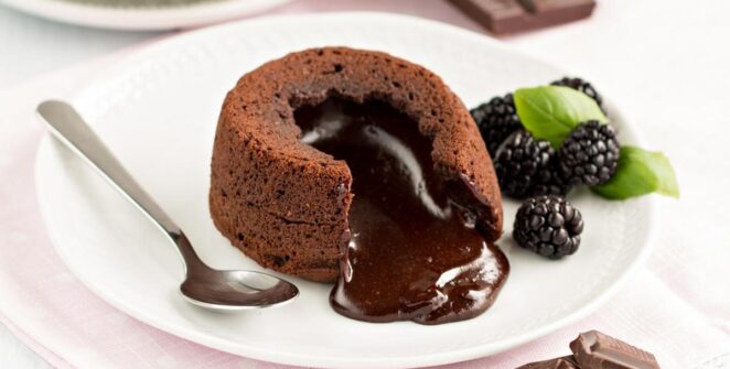Lava cake cokelat dengan bagian luar yang lembut dan isi cokelat lumer di dalam, disajikan dengan es krim vanila dan buah segar