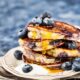Tumpukan pancake blueberry fluffy lembut dengan siraman maple syrup dan blueberry segar